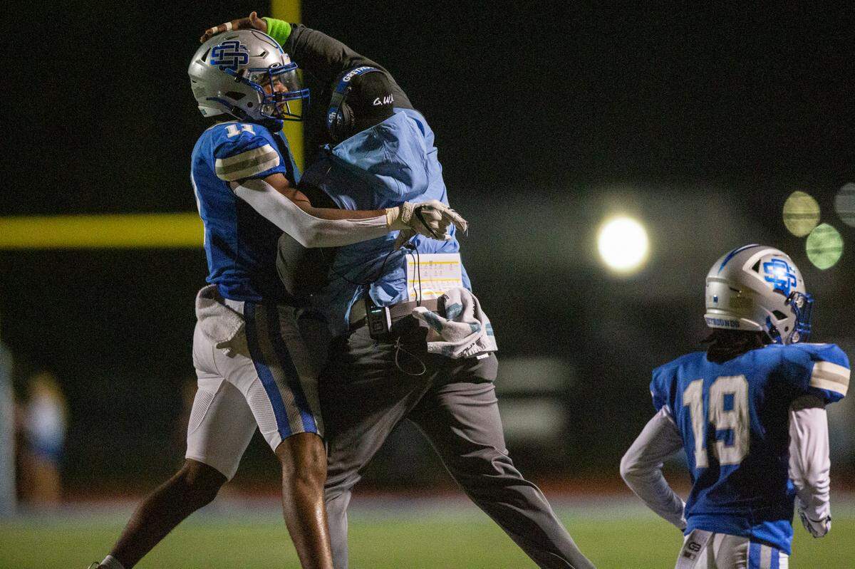 Ocean Springs’ Eric Moore Jr. and defensive line coach Kendall Davis celebrate during a game against Gulfport at Greyhound Stadium in Ocean Springs on Friday, Oct. 28, 2022.