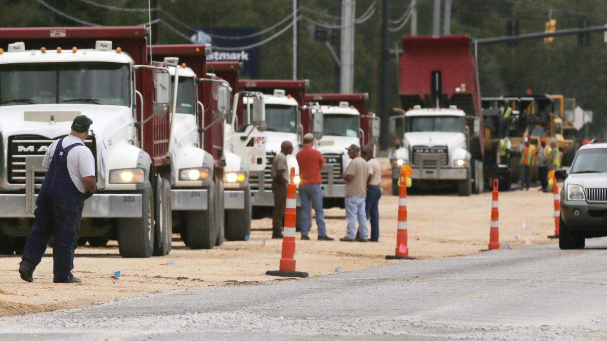 JOHN FITZHUGH/SUN HERALDTruck drivers for Huey P. Stockstill wait for their turn to unload asphalt as they pave a section of Popp's Ferry Road in Biloxi on Tuesday.