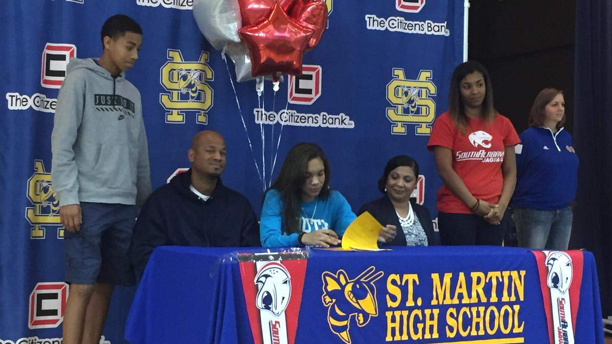 PATRICK OCHS/SUN HERALD 
 St. Martin senior Savannah Jones, center, signed to play basketball at South Alabama on Friday. Jones was joined on stage by her mother, Sarah, her father and brother, Roshaun, and sister, Sierra.