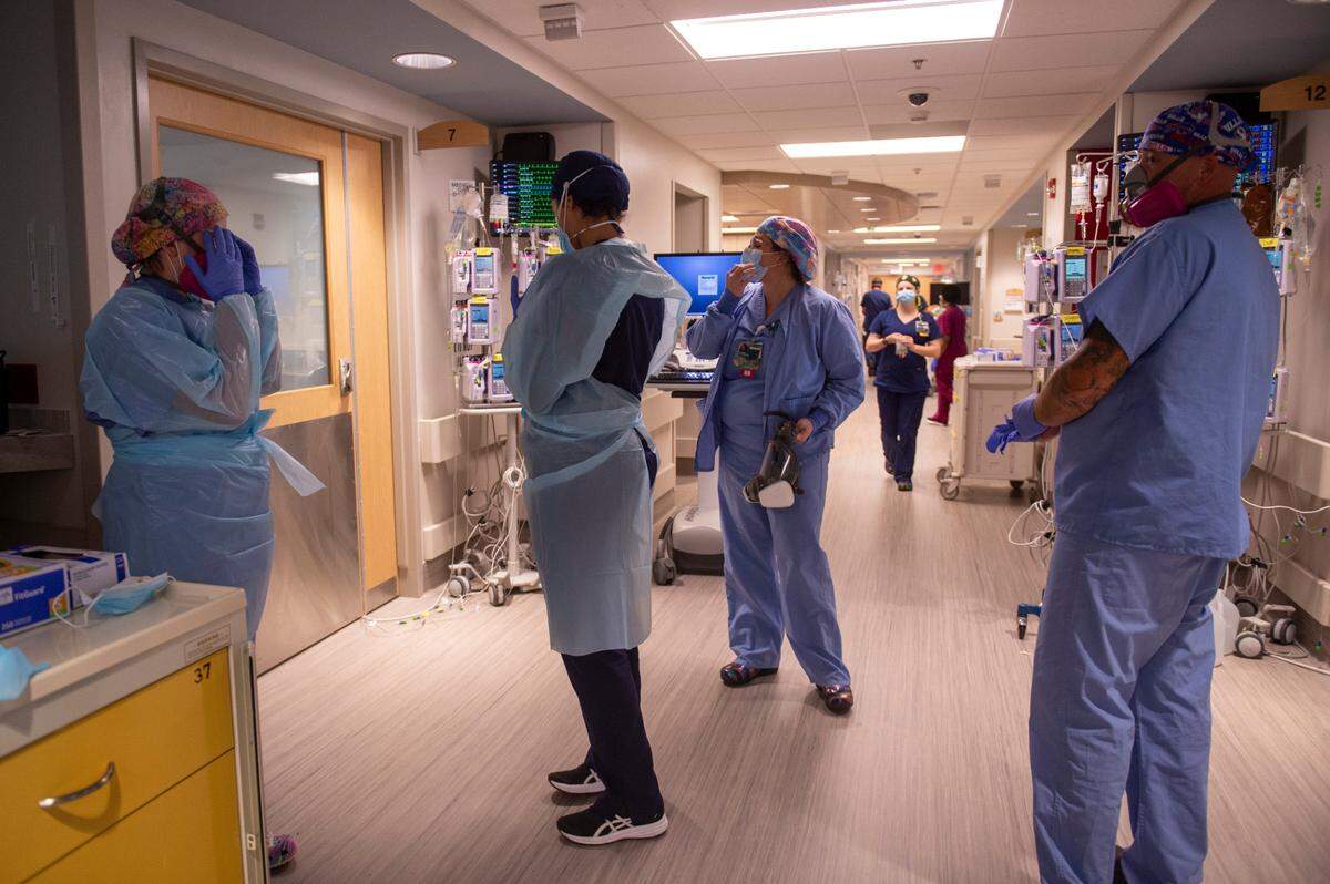 Nurses put on personal protective equipment including gloves and gowns before entering a COVID-19 patient’s room to turn a patient onto their stomach at the ICU at Memorial Hospital in Gulfport on Wednesday, Aug. 11, 2021.