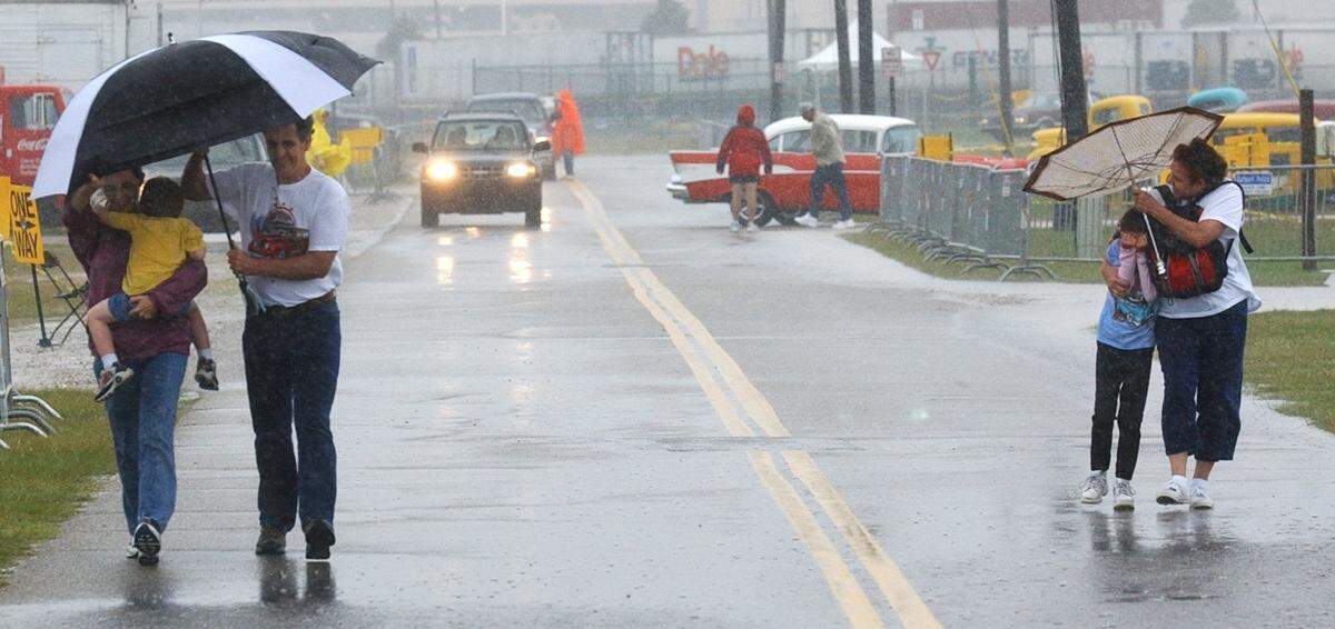 Cruisin’ The Coast spectators make their way to their carsat Jones Park in Gulfport on October 9, 2004, as a squawl from Tropical Storm Matthew pelts them with rain.