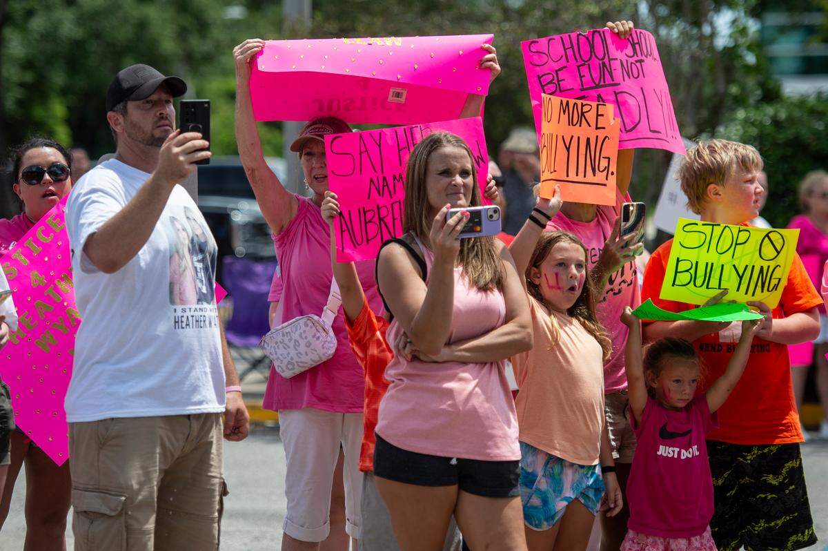 Protesters in support of Heather Wyatt and Aubreigh Wyatt hold signs, take photos and livestream on various social media platforms outside the Jackson County Courts building on Thursday, July 18, 2024, as Heather Wyatt participates in a chancery court hearing inside the courthouse.