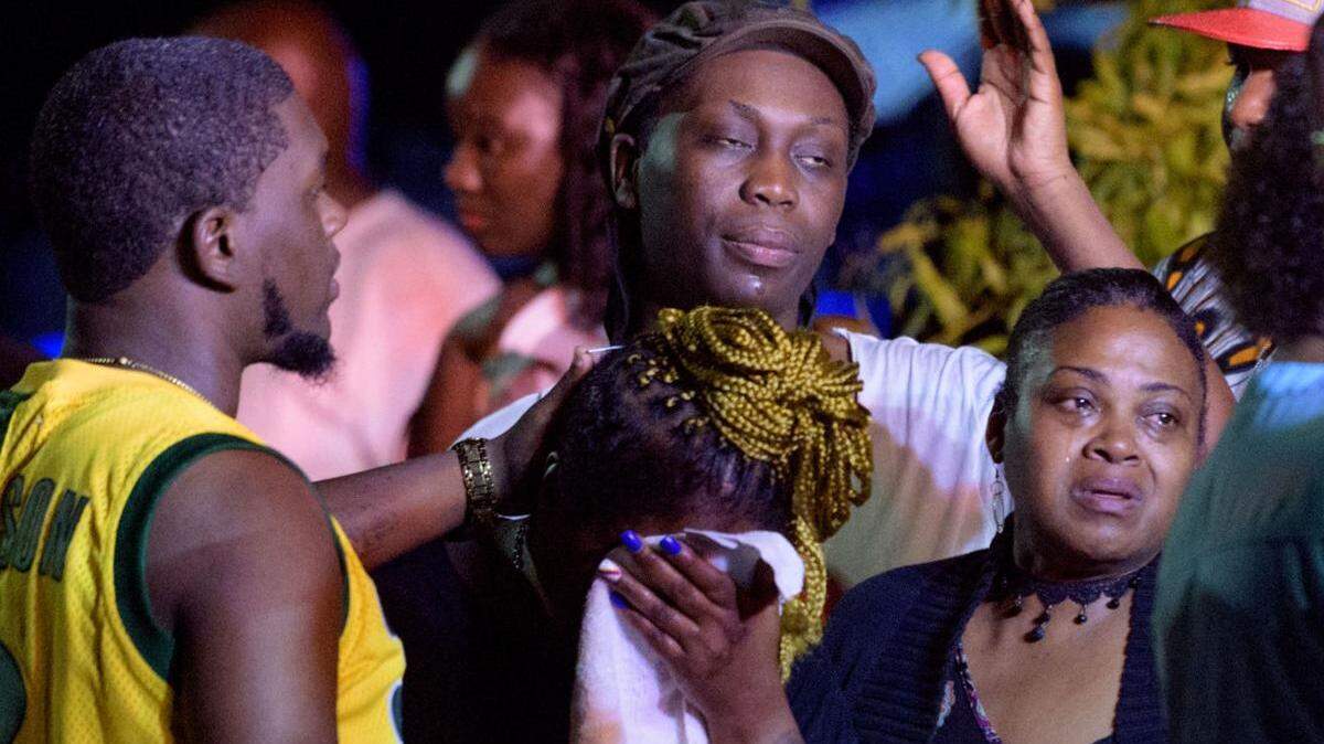 People react at the scene of the 3400 block of South Claiborne Avenue where three people are dead and seven more injured in a shooting in New Orleans, Louisiana, Saturday July 28, 2018.