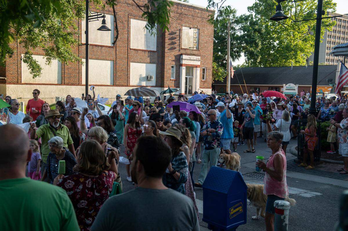 Parade goers wave handkerchiefs and hold umbrellas during a second-line funeral and celebration for the life of Carl, a beloved rooster who was killed in April, in Ocean Springs on Tuesday, May 10, 2022.