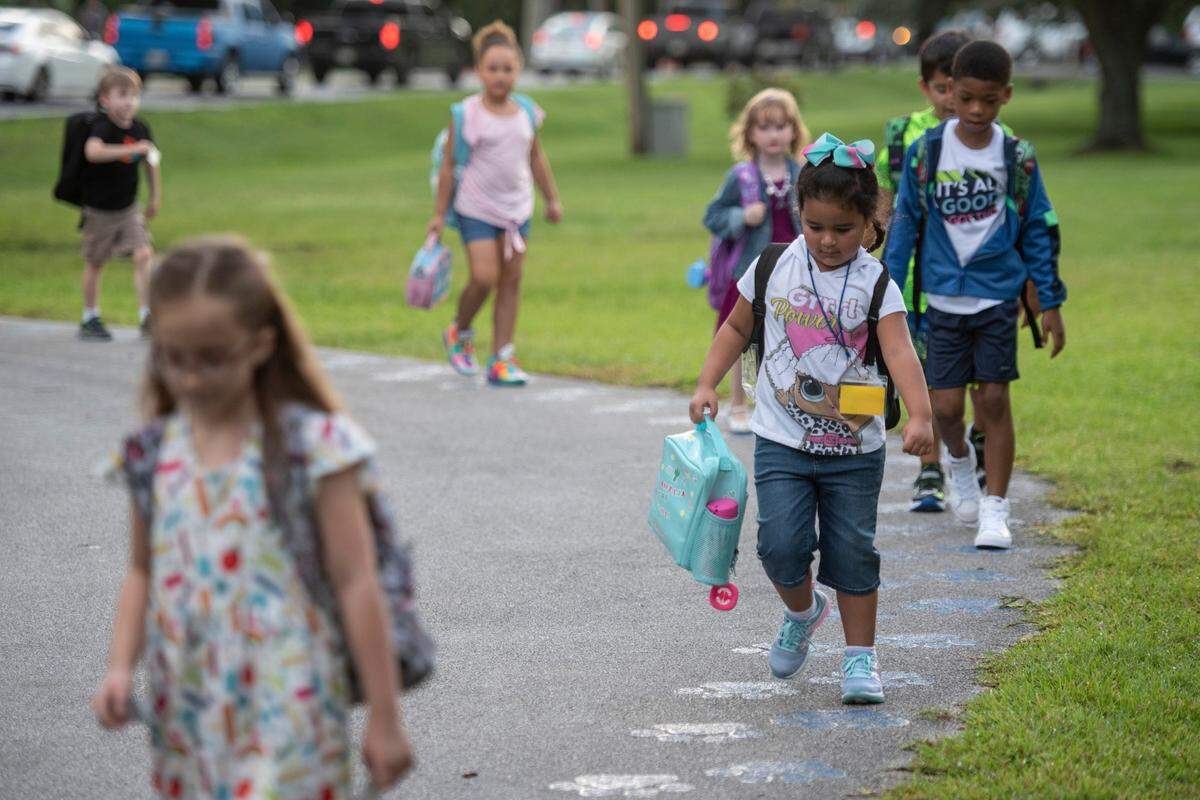 Elementary school students follow a walkway from the bus to their classes on the first day of school at Magnolia Park Elementary on Friday, Aug. 5, 2022.