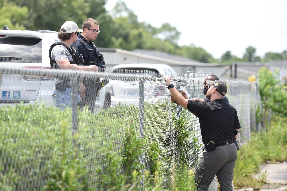 Law enforcement officials talk at the scene of an officer-involved shooting at Dedeaux Road and Three Rivers Road in Gulfport on Wednesday, May 22.