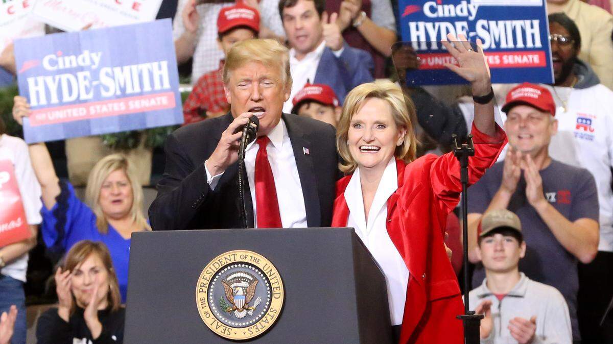 President Donald Trump speaks as Sen. Cindy Hyde-Smith waves to the crowd at the Mississippi Coast Coliseum in Biloxi on Monday, Nov. 26, 2018.