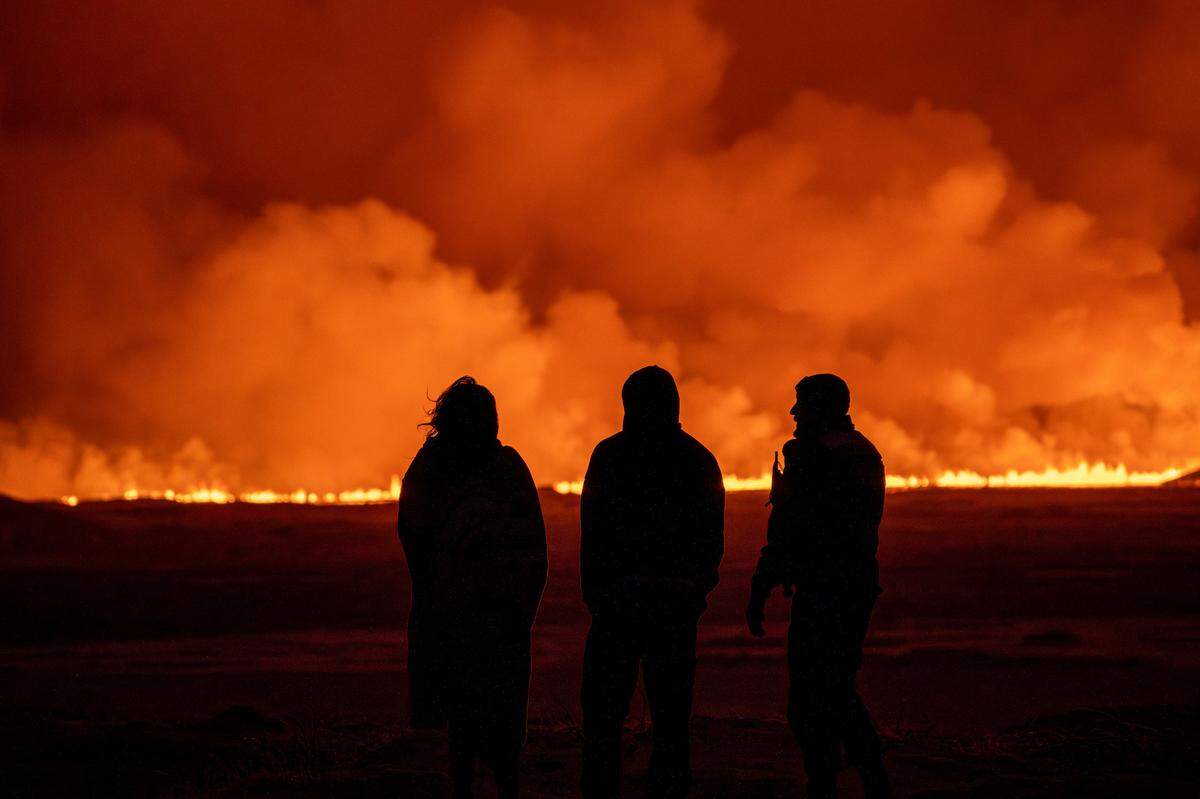 People watch as the night sky is illuminated by the eruption of a volcano in Iceland earlier this month.
