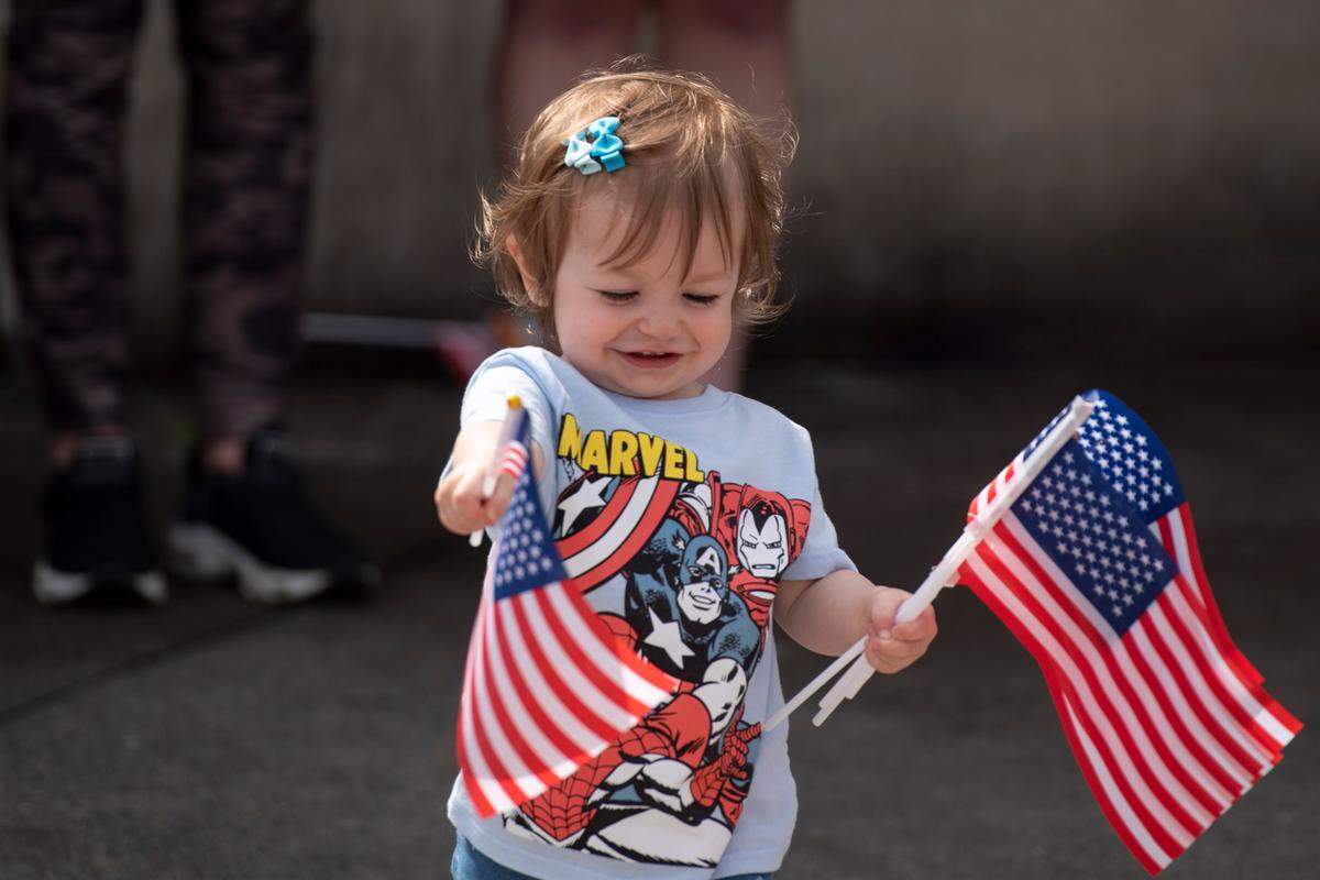 15-month-old Mabel Gates waves flags as she awaits the arrival of Naval Mobile Construction Battalion 1 as they return home from deployment on Thursday, March 13, 2025, to Naval Construction Battalion Center Gulfport.