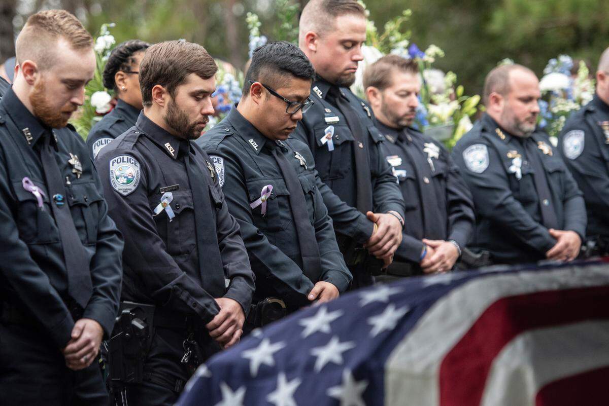 Bay St. Louis law enforcement officers bow their heads over the caskets of Bay St. Louis police officers Sgt. Steven Robin and Branden Estorffe during their gravesite ceremonies at Gardens of Memory cemetery in Bay St. Louis on Wednesday, Dec. 21, 2022. Robin and Estorffe were killed responding to a call at a Motel 6 on Dec. 14.