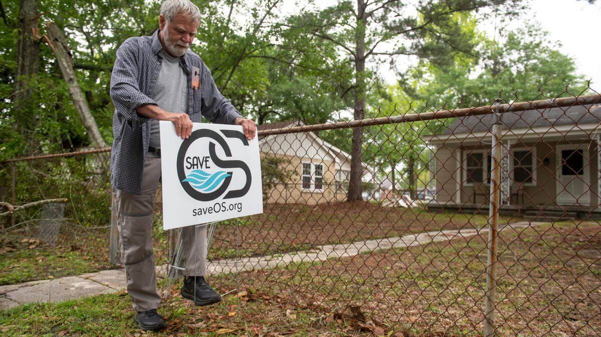 Tom Ehrensing puts a SaveOS sign in a yard on Bowen Avenue in Ocean Springs on Thursday, April 11, 2024. Save Ocean Springs, an organization to inform residents about city issues, opposes commercialization of Front Beach.