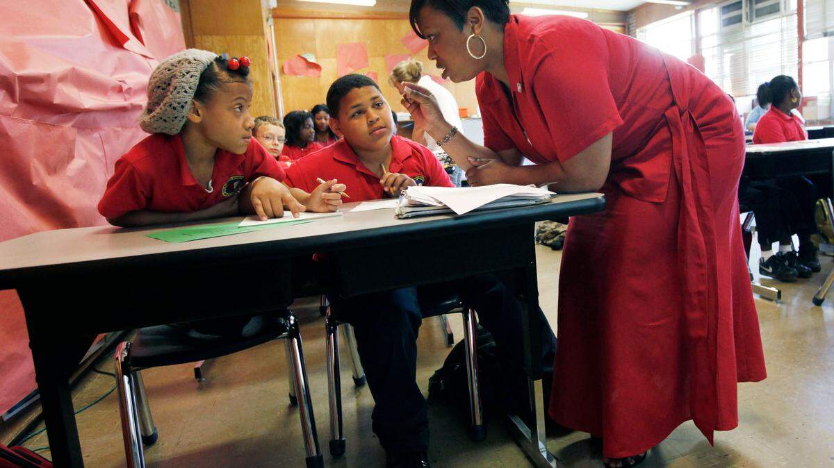 In this photo taken, April 7, 2010, Trenise Duvernaytalks to Miracle Lee, left, and Danny Dinet, center, as she teaches fourth grade math class at the Alice M. Harte Charter School in New Orleans.