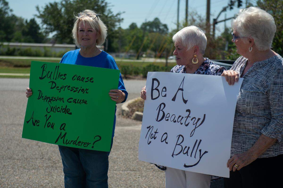 Karla Owens and family hold up signs against bullying outside Ocean Springs Middle School in Ocean Springs on Thursday, Sept. 7, 2023.