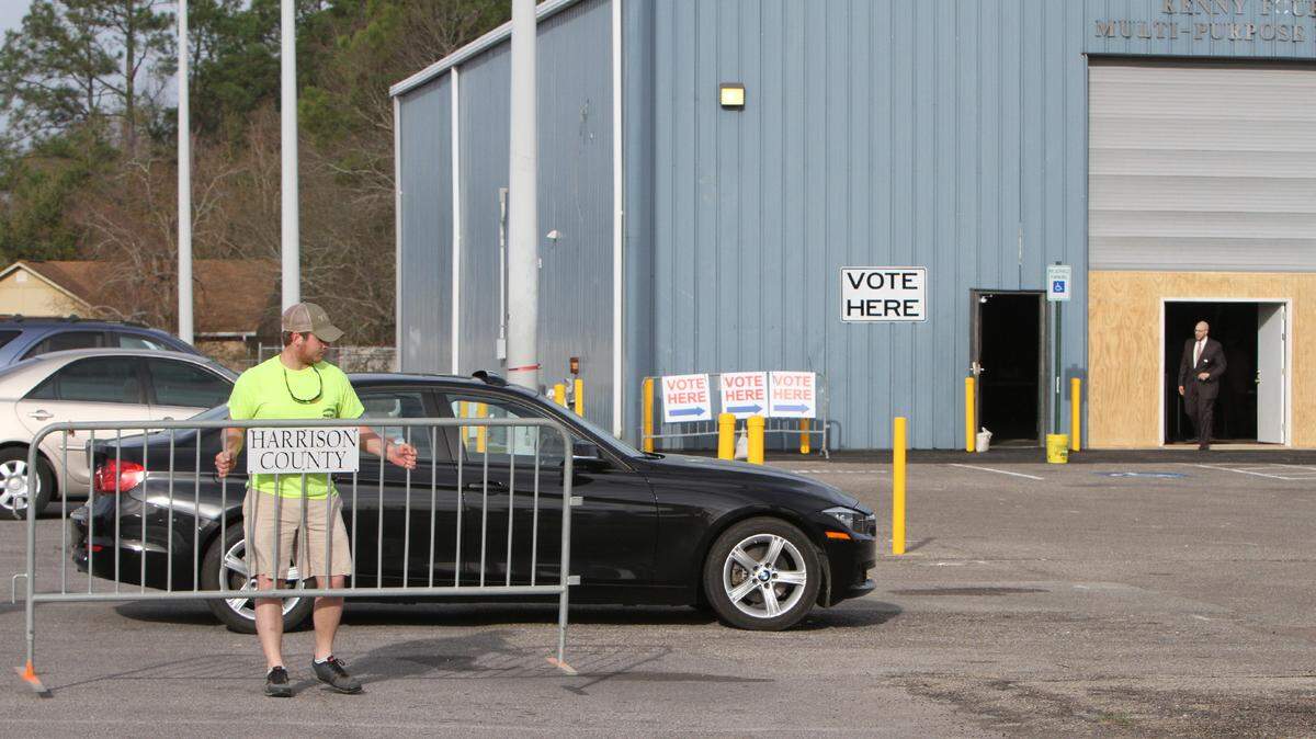 JOHN FITZHUGH/SUN HERALDHarrison County road department employee Tyler Miller puts up a barricade to help direct election-day traffic at the Kenny Fornier multi-purpose building in D'Iberville on Tuesday March 8, 2016. The polling place was moved from the D'Iberville Civic Center next door because of a booking conflict.