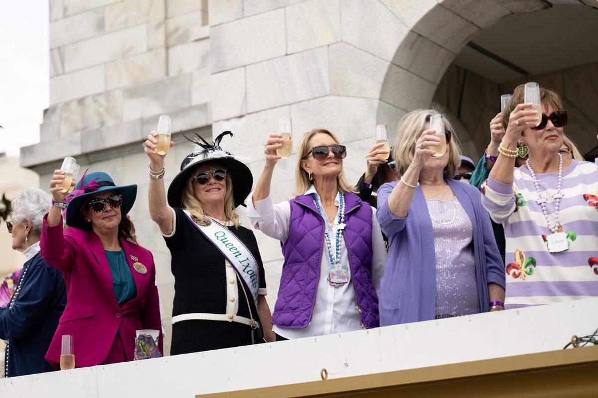 Parade attendees lift their glasses to give a toast as they kick off the Gulf Coast Carnival Association’s Fat Tuesday parade in Biloxi on Tuesday, Feb. 17, 2026.