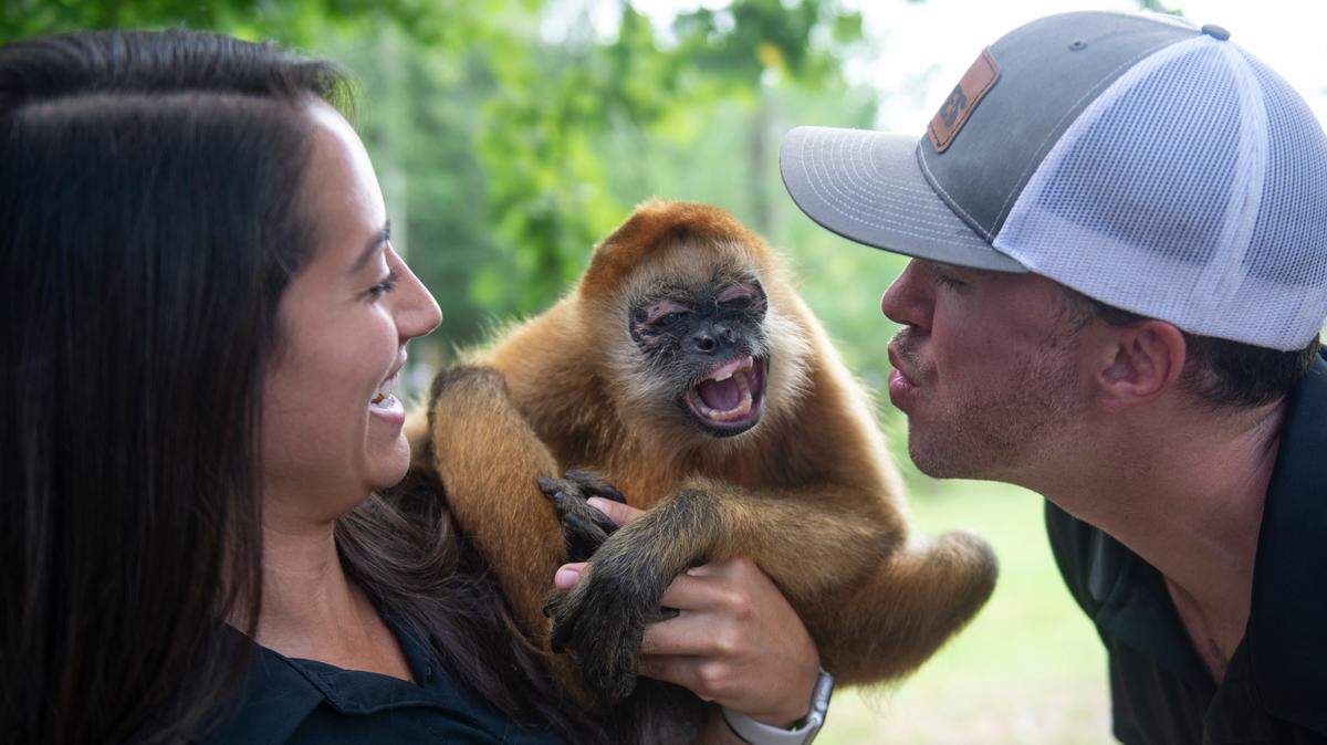 Bre Anderson, staff manager at Wild Acres, and Cody Breland, owner of Wild Acres, make faces with Kiki, a spider monkey, outside his enclosure at Wild Acres in McHenry on Thursday, July 6, 2023.