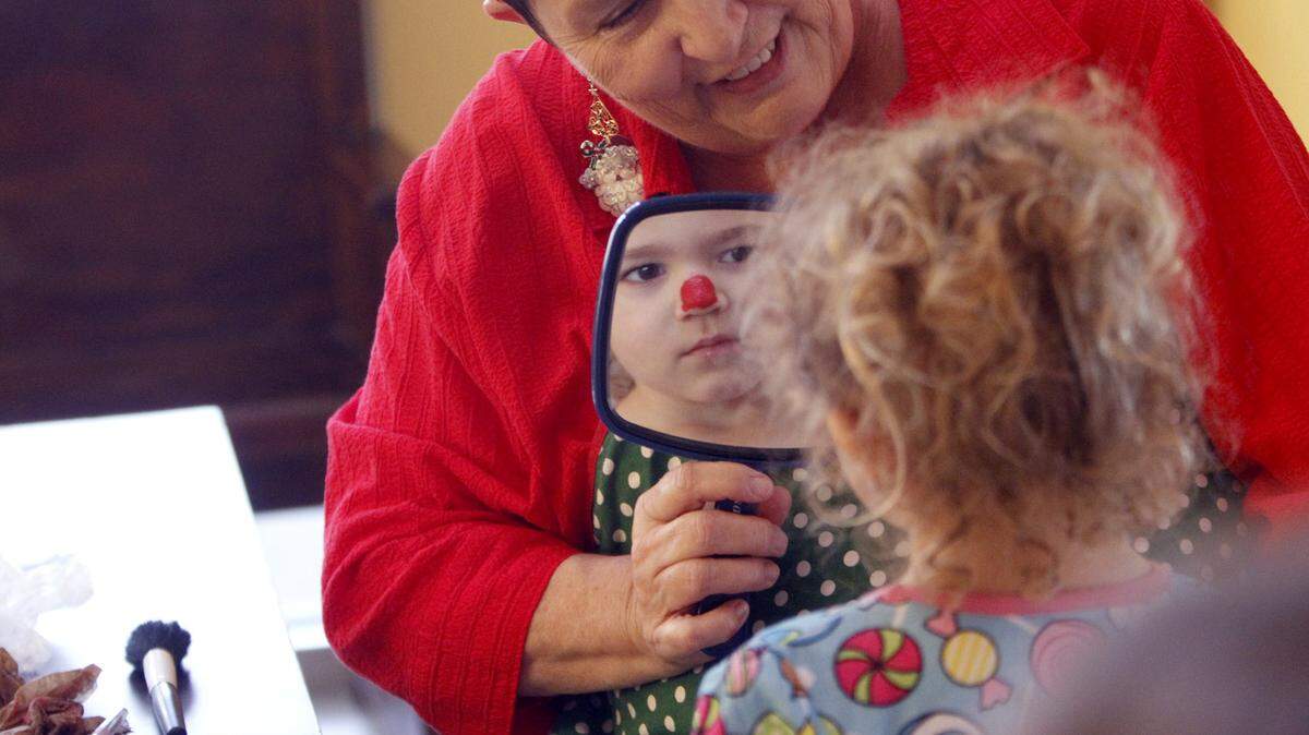 TIM ISBELL/SUN HERALD 
 Kathy Burns shows Bailey Dellenger her new look after Burns painted her nose red, Saturday, Nov. 28, 2015. Dellenger was attending Jammies and Jingles, a pancake breakfast that kicked off the Christmas season at Lynn Meadows Discovery Center in Gulfport.