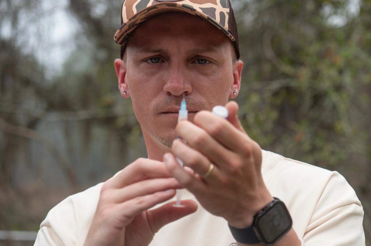Joshua Holland prepares to vaccinated a wild raccoon for distemper in Bay St. Louis on Friday, Feb. 24, 2023.