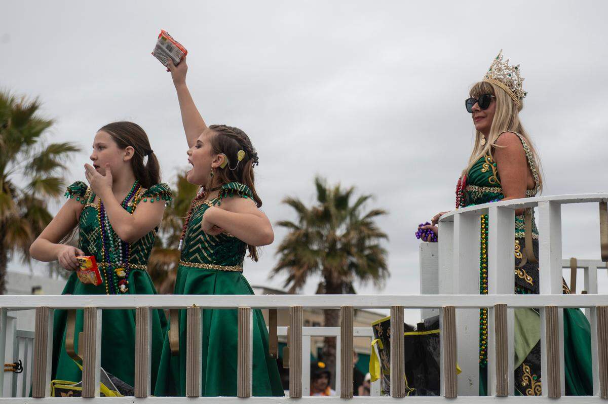 Float riders throw ramen packets from the queen’s float during the Krewe of Gemini parade in downtown Gulfport on Saturday, Feb. 10, 2024.