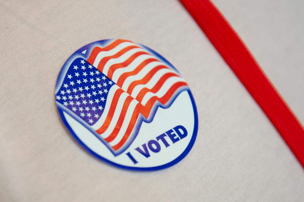 An election worker wears a voting sticker at Orange Grove Community Center, a voting precinct in Harrison County, on Election Day, Tuesday, Nov. 7, 2023.