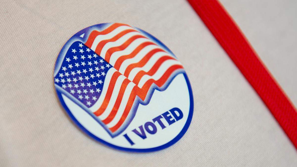 An election worker wears a voting sticker at Orange Grove Community Center, a voting precinct in Harrison County, on Election Day, Tuesday, Nov. 7, 2023.