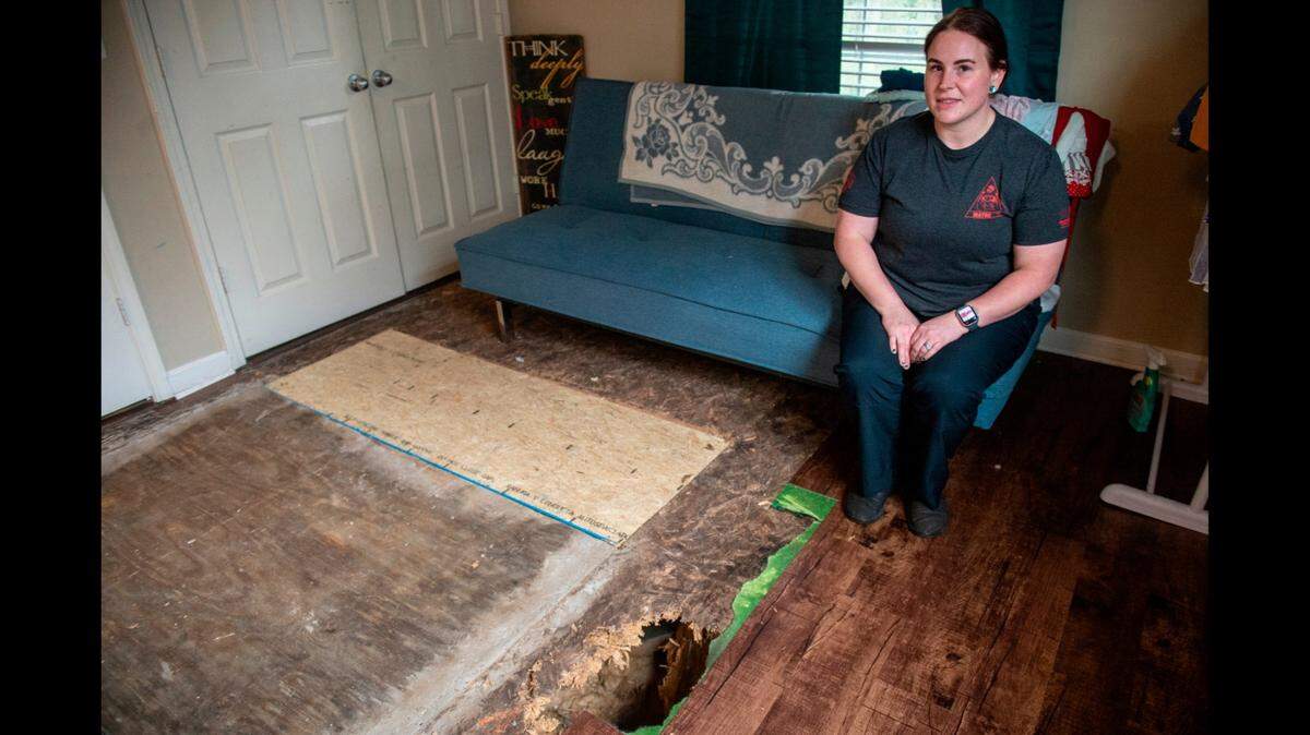 Sarah Hampton poses for a portrait near a hole in the floor of her rental home in Pass Christian’s North Street Villas on Wednesday, Oct. 25, 2023. Hampton says the floor was not sufficiently repaired and is getting worse. Since the photo was taken, the subdivision’s management company has moved to have her evicted for failing to pay full rent, which Hampton did not believe she should owe for a house in this condition.
