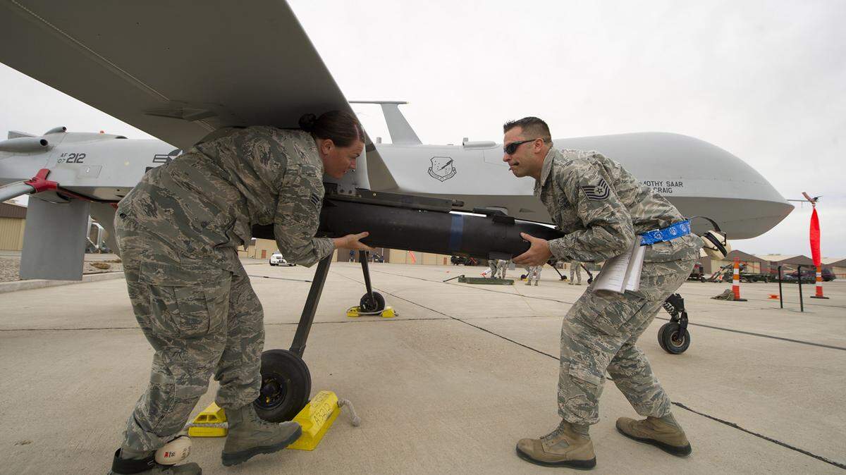 An Air Force crew loads a missile on a Predator drone. (Airman 1st Class Michael Shoemaker/US Air Force)