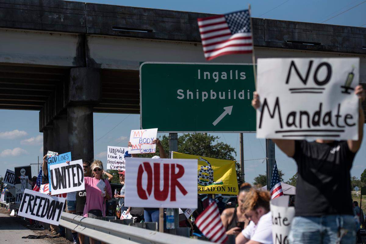Protestors wave flags and signs on the side of Highway 90 during a protest against Ingalls’ vaccine mandate in Pascagoula on Friday, Oct. 8, 2021.