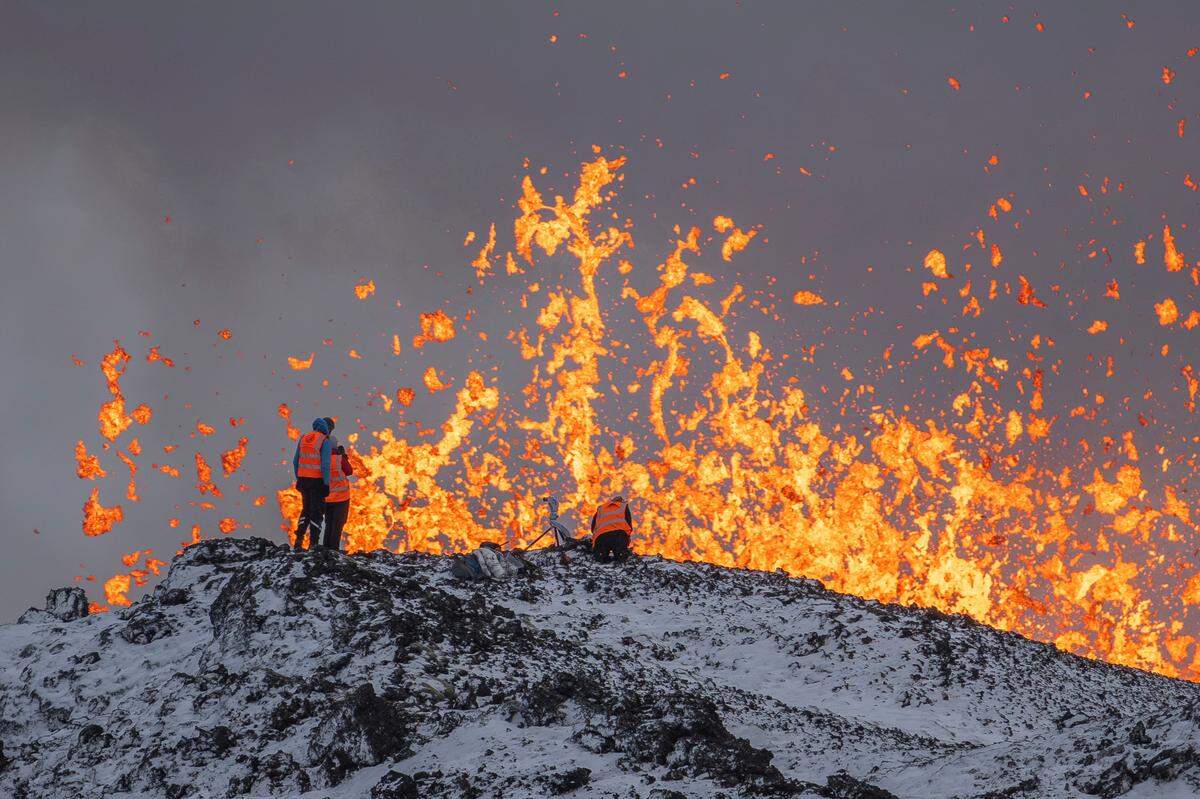 Scientist of the University of Iceland take measurements and samples standing on the ridge in front of the active part of the eruptive fissure of an active volcano in Grindavik on Iceland’s Reykjanes Peninsula, Tuesday, Dec. 19, 2023. (AP Photo/Marco Di Marco)