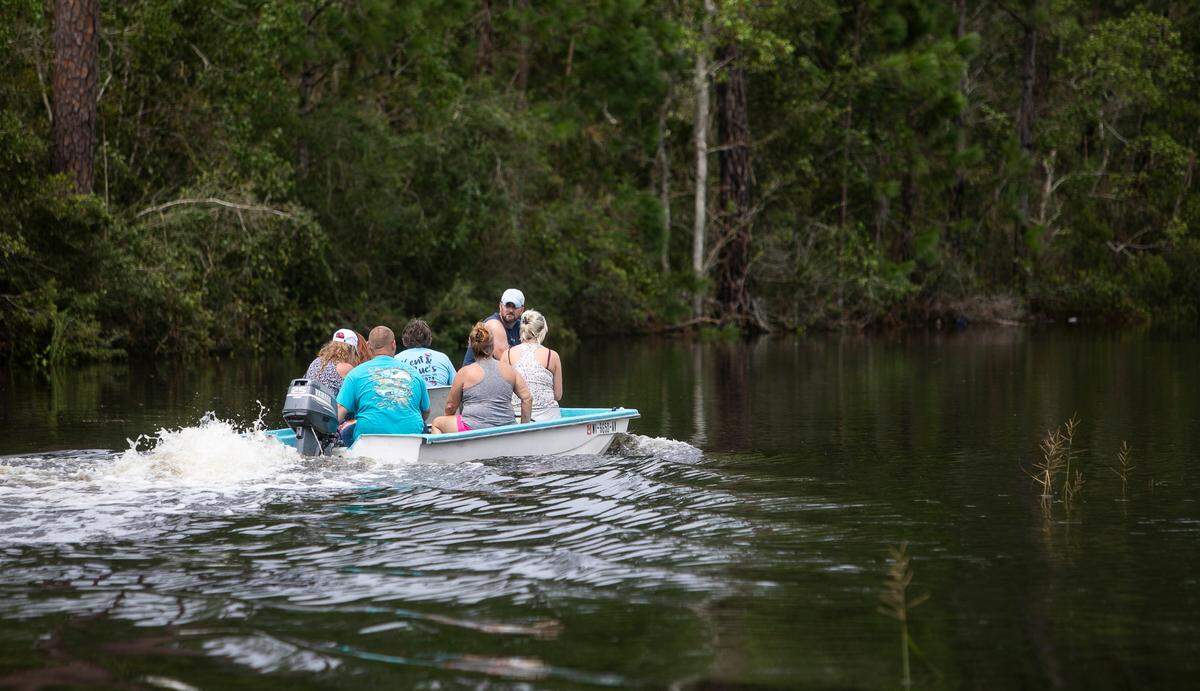 A boat full of people cruises Whitney Street in the Shoreline Park community of Bay St. Louis on Aug. 30, 2021, after Hurricane Ida caused storm surge in the area.