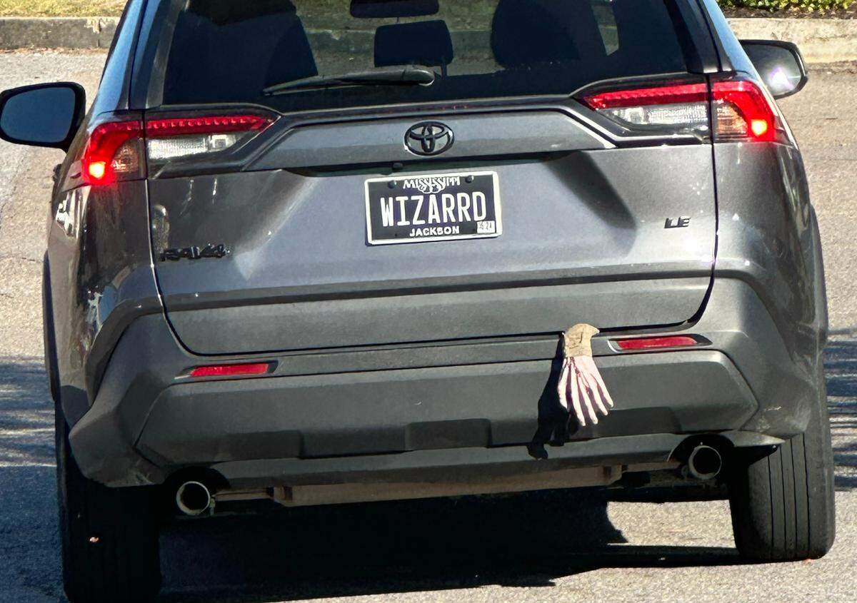 The fake hand hanging out the back just adds to the spookiness of this “WIZARRD” license plate.