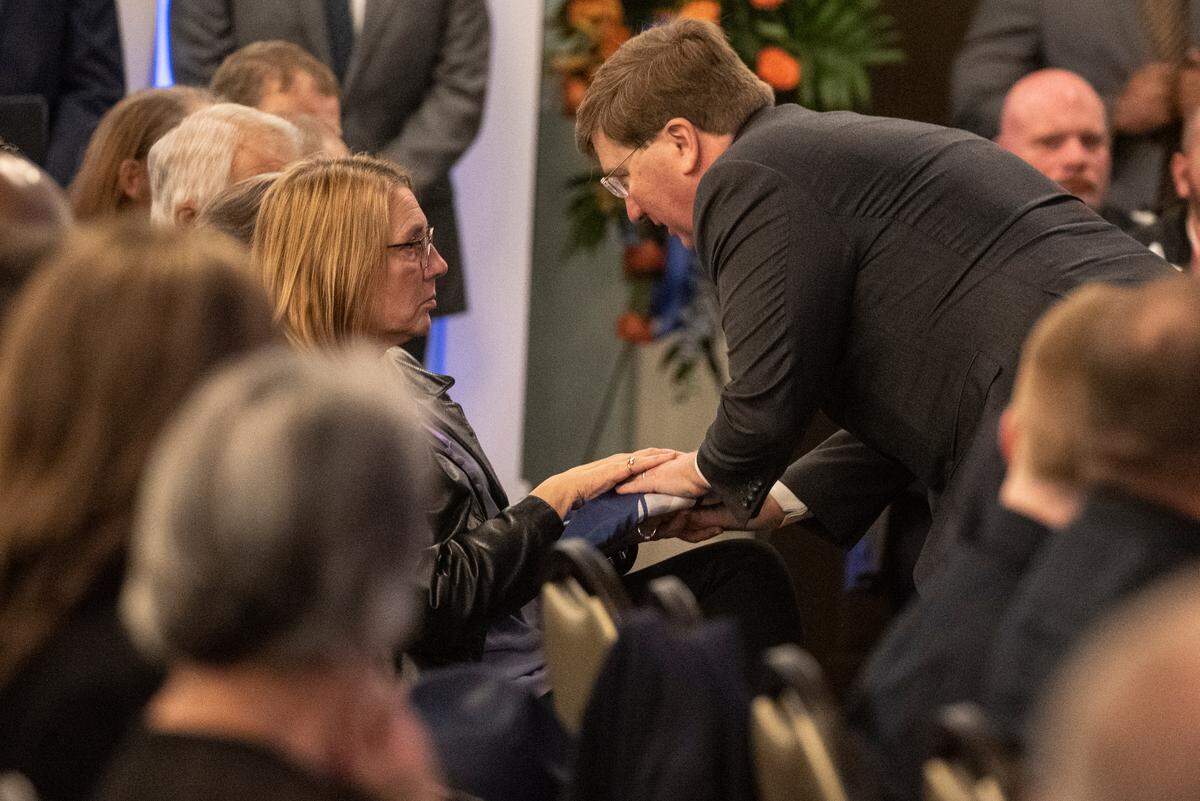 Gov. Tate Reeves presents a folded Mississippi state flag to the family of fallen officer Steven Estorffe during the funeral for Bay St. Louis police officers Sgt. Steven Robin and Branden Estorffe at the Bay St. Louis Community Center in Bay St. Louis on Wednesday, Dec. 21, 2022. Robin and Estorffe were killed responding to a call at a Motel 6 on Dec. 14.
