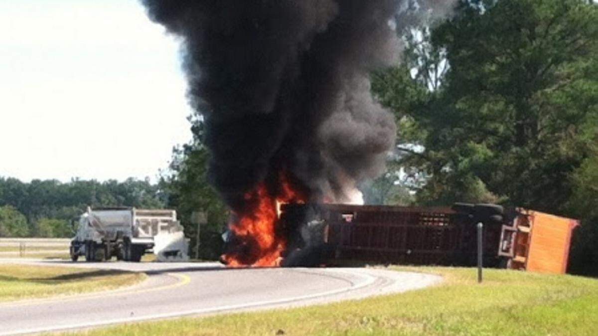 An overturned semi-truck is engulfed in flames on an Interstate 10 exit ramp in Mobile Thursday. Four Coast Guardsmen, of Coast Guard Sector Mobile, witnessed the accident,and pulled the unconscious driver from the truck's cab just seconds before it was engulfed in flames. (U.S. Coast Guard photo courtesy of Coast Guard Sector Mobile)