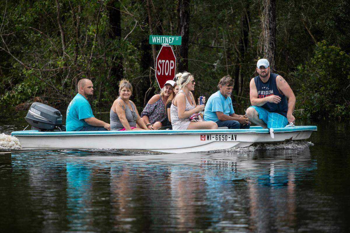 A boat full of people cruises Whitney Street in the Shoreline Park community of Bay St. Louis on Aug. 30, 2021, after Hurricane Ida caused storm surge in the area.