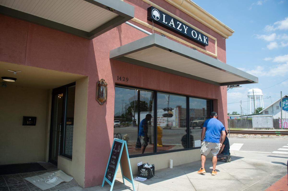 Workers put decals on the windows at Lazy Oak Brunch + Bistreaux in Gulfport on Wednesday, Aug. 7, 2024 — their first day open.