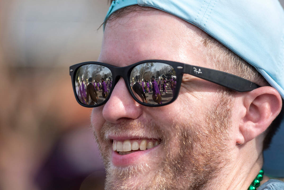 A marching band reflects in a man’s glasses during the Ocean Springs Elks Club Mardi Gras Parade in Ocean Springs on Saturday, Feb. 15, 2025.