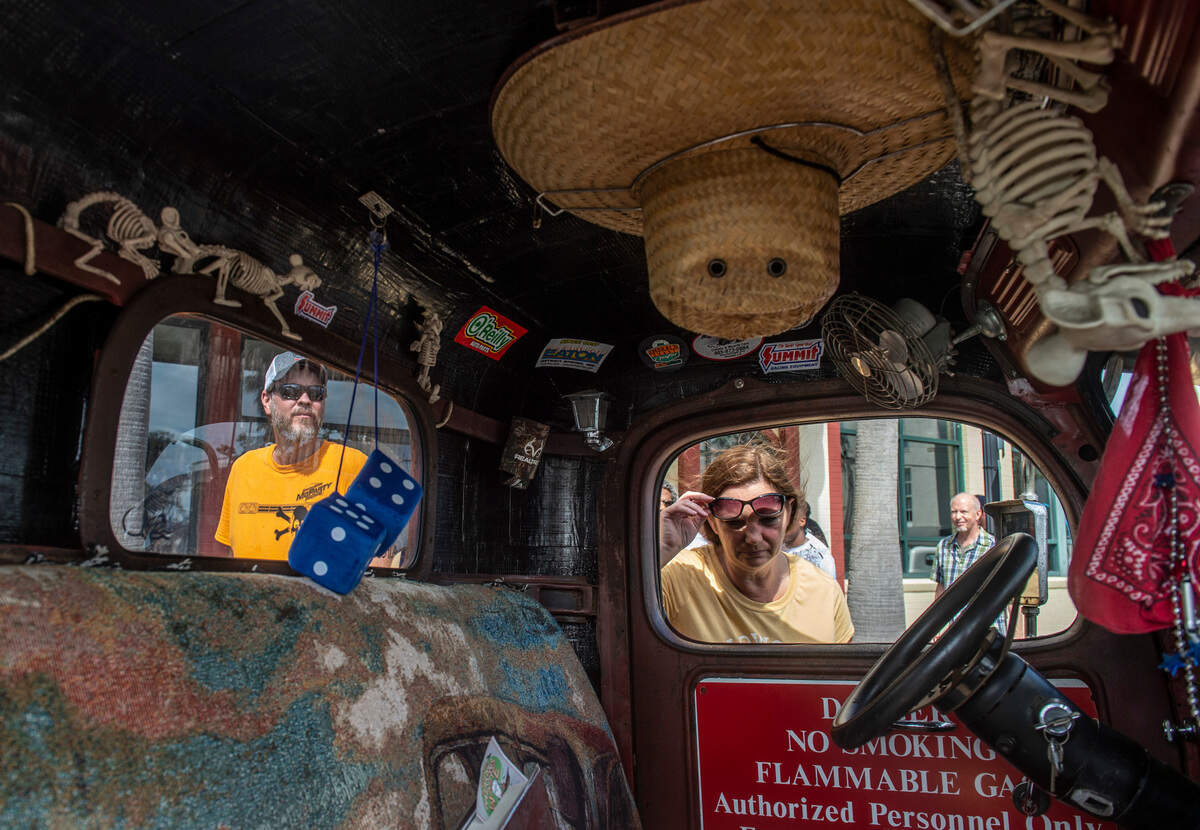 View the Cruise attendees peer into a car outfitted with plastic rat skeletons and stickers on Sunday, Oct. 3, 2021.