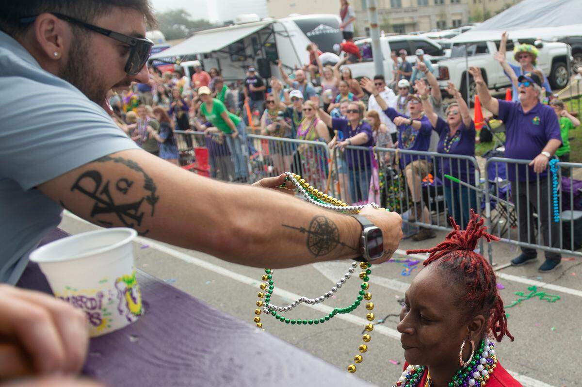 A float rider places beads on a woman’s head during the Gulf Coast Carnival Association Mardi Gras parade in Biloxi on Tuesday, Feb. 21, 2023.