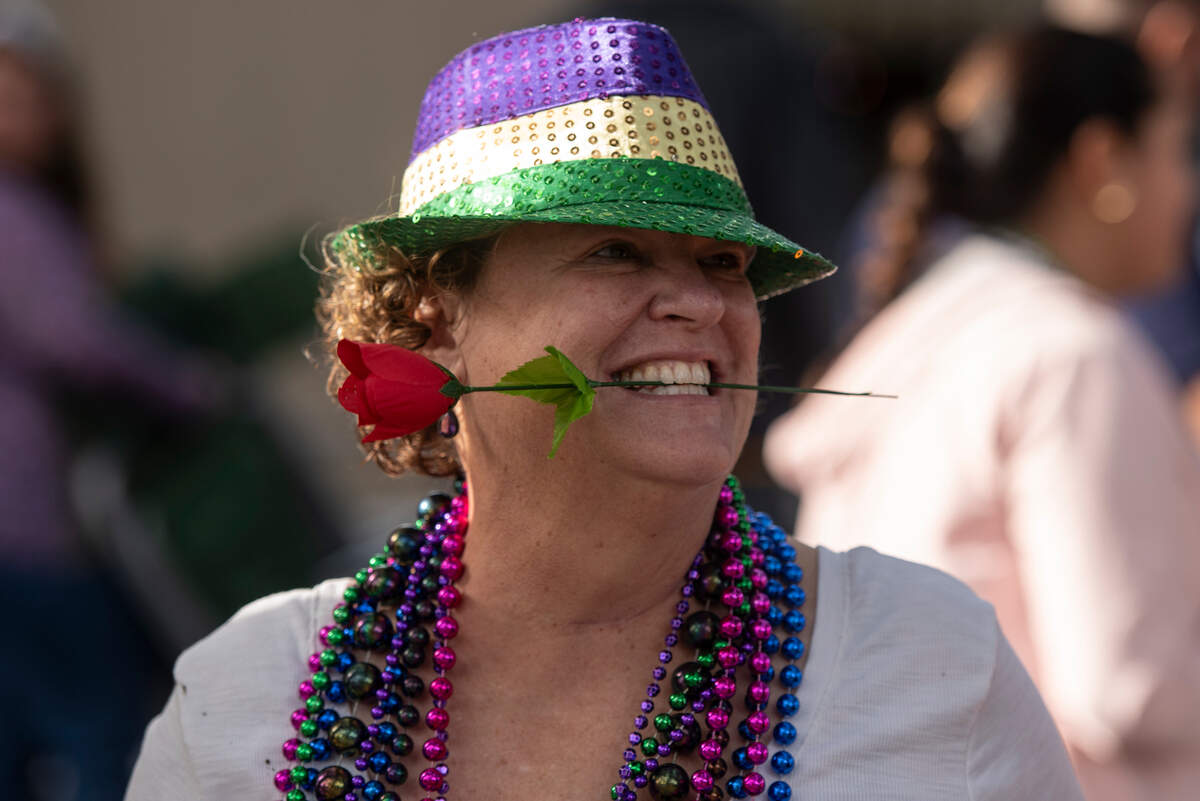A woman holds a plastic rose in her mouth during the Ocean Springs Elks Carnival Parade in downtown Ocean Springs on Saturday, Jan. 27, 2024.