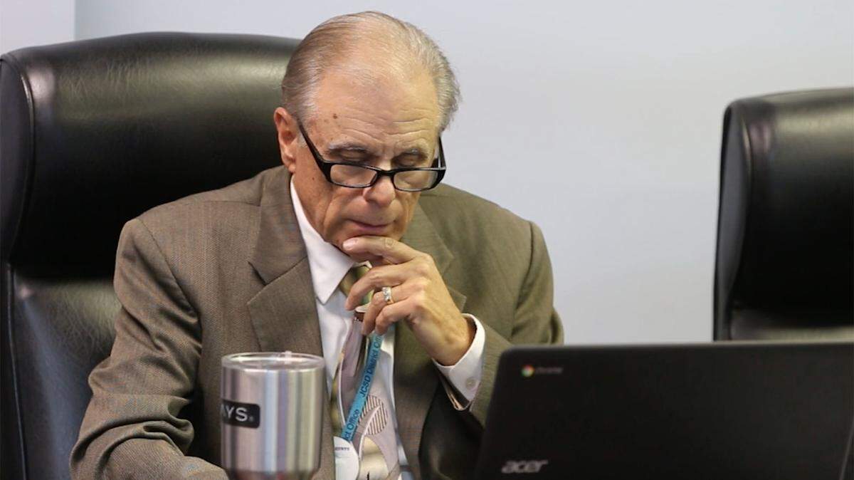 Jackson County Superintendent of Education Barry Amacker attends a school board meeting on May 14,  while a parent speaks about mistreatment of special-needs students.