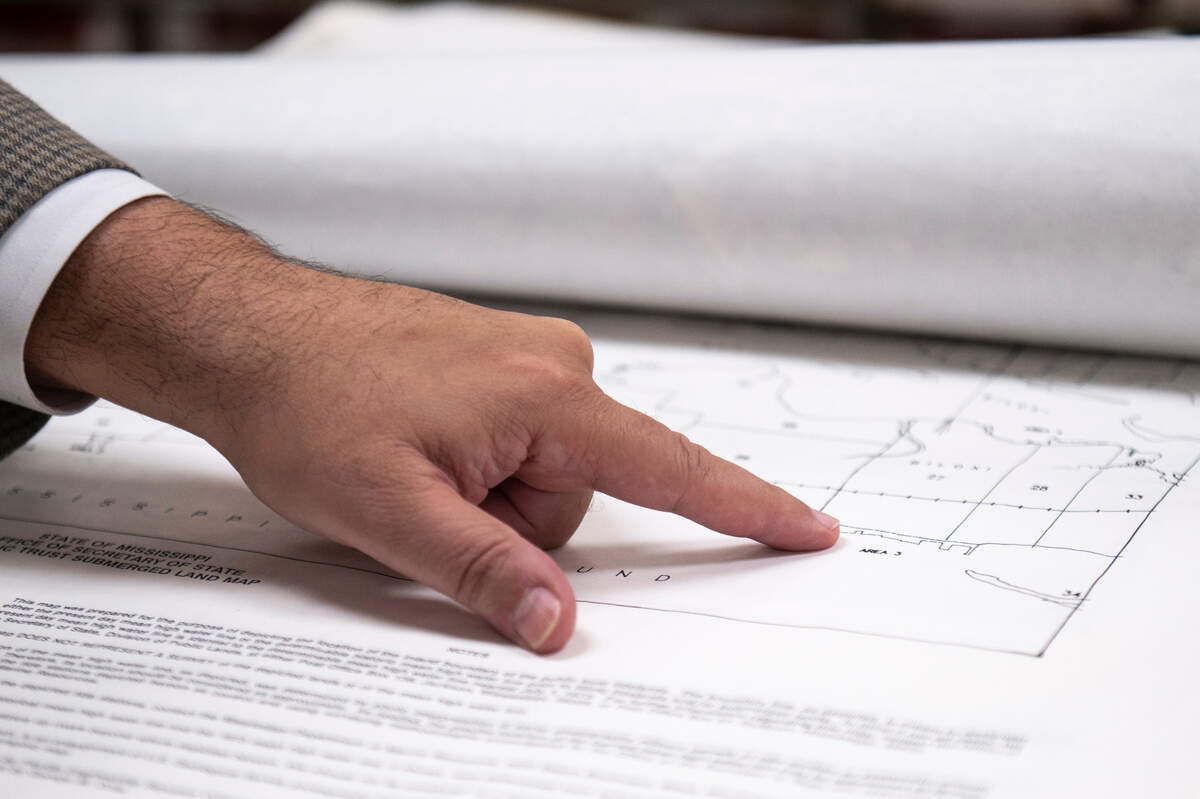 Biloxi city attorney Peter Abide looks through maps of tidelands in the Chancery Clerk’s office in Biloxi on Monday, March 11, 2024. According to Abide, the maps still in use were previously ruled illegal by a judge.