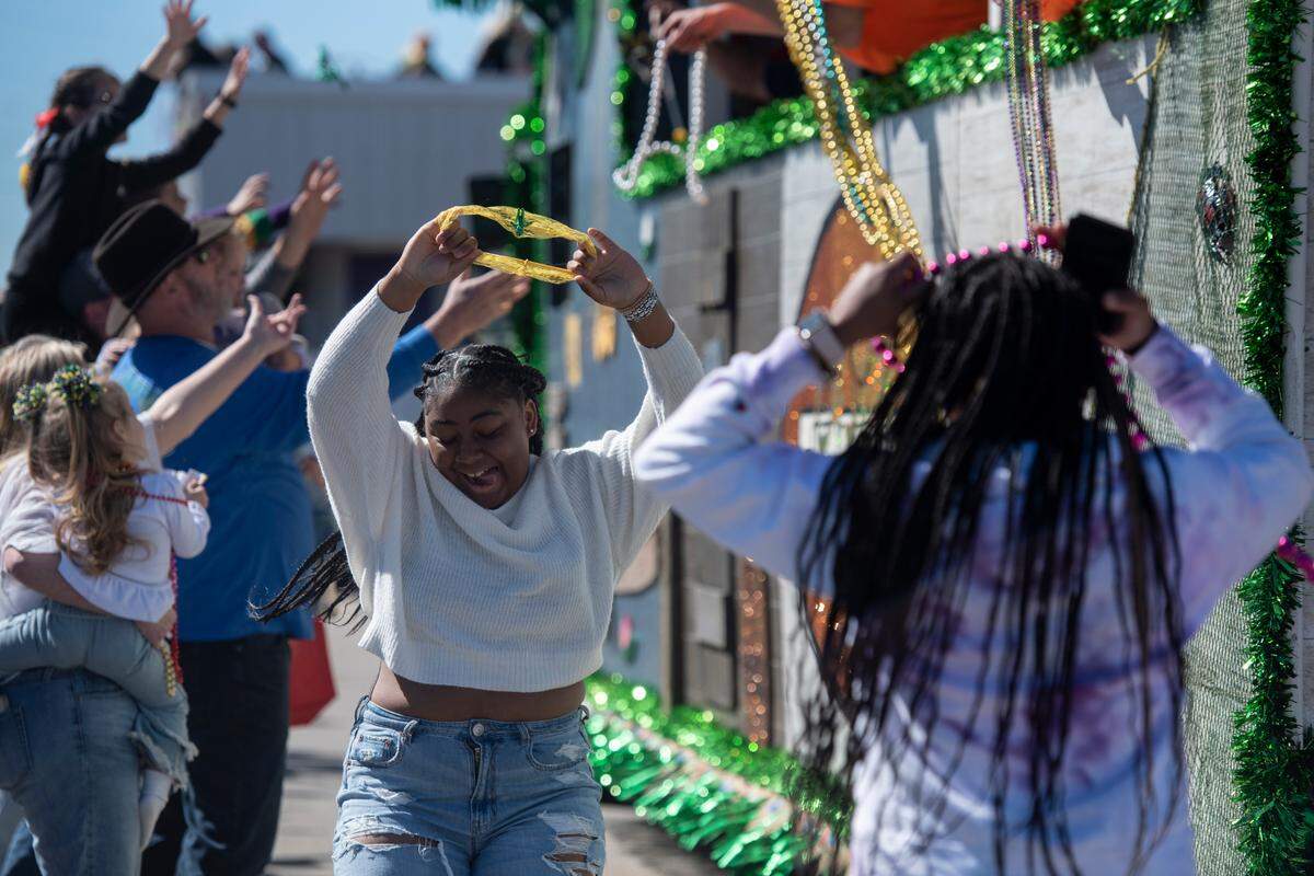 A girl catches a headband during the Krewe of Nereids Mardi Gras parade on Highway 90 in Bay St. Louis on Sunday, Feb. 12, 2023.