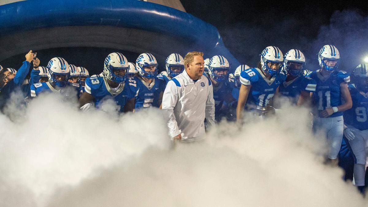 Ocean Springs coach Blake Pennock leads the Greyhounds onto the field for a playoff game against Pearl at Greyhound Stadium in Ocean Springs on Friday, Nov. 12, 2021.