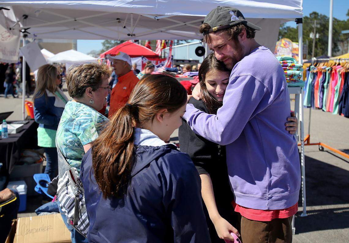 Steve Johnson, better known as Scuba Steve, hugs long time friend Emily Fertitta while selling his shirts at the D'Iberville BBQ Throwdown & Festival.