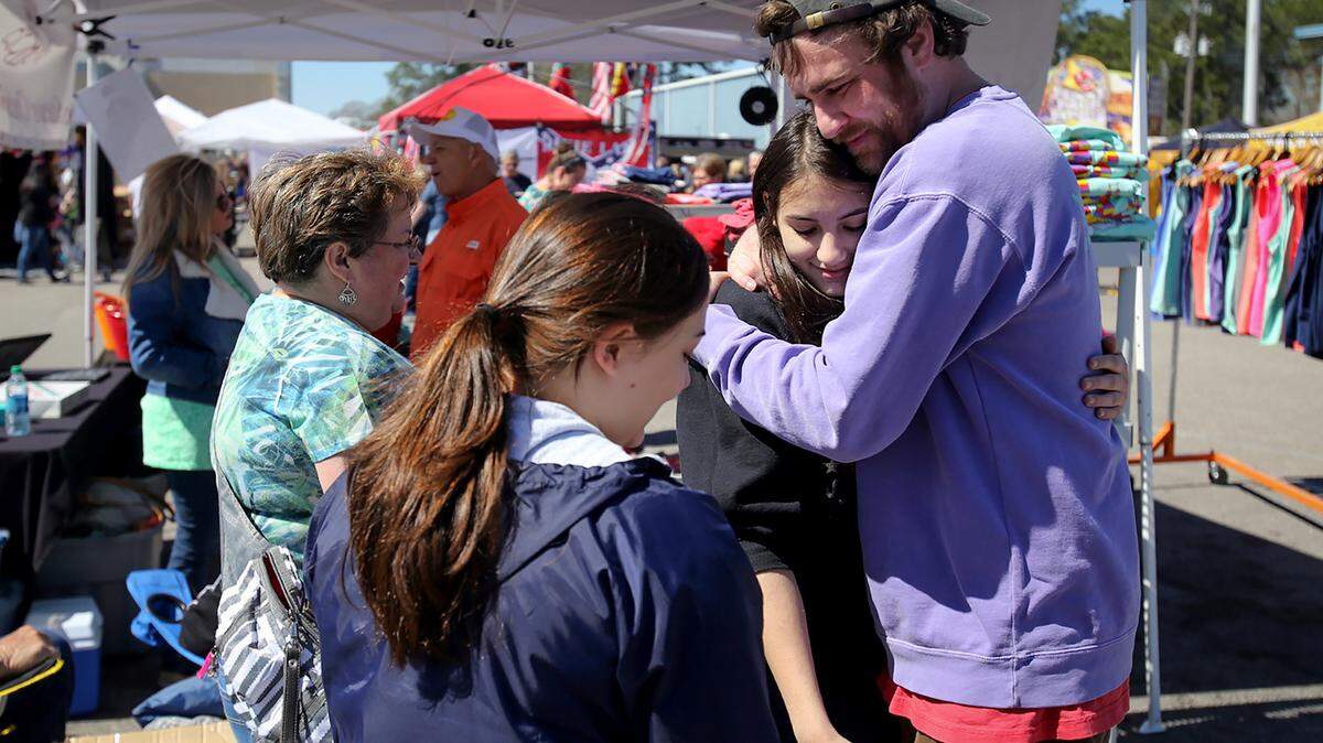 AMANDA McCOY/SUN HERALDSteve Johnson, better known as Scuba Steve, hugs long time friend Emily Fertitta while selling his shirts at the D'Iberville BBQ Throwdown & Festival on Saturday. Johnson said that his cancer has returned and that he will have to undergo surgery next week, followed by another six months of chemotherapy. Also pictured are Annette Fertitta, left, and Emily Fertitta.