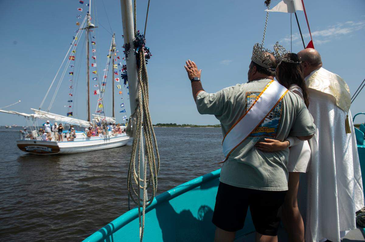 Msgr. Dominick Fullam and the Shrimp King and Queen wave to a boat during the Blessing of the Fleet in Biloxi on Sunday, May 28, 2023.