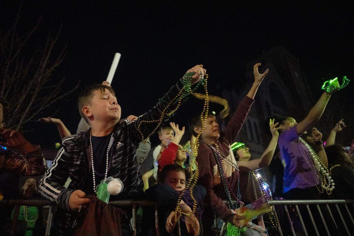 Children catch Mardi Gras beads from parade floats during the Krewe of Neptune parade in Biloxi on Saturday, Feb. 14, 2026.