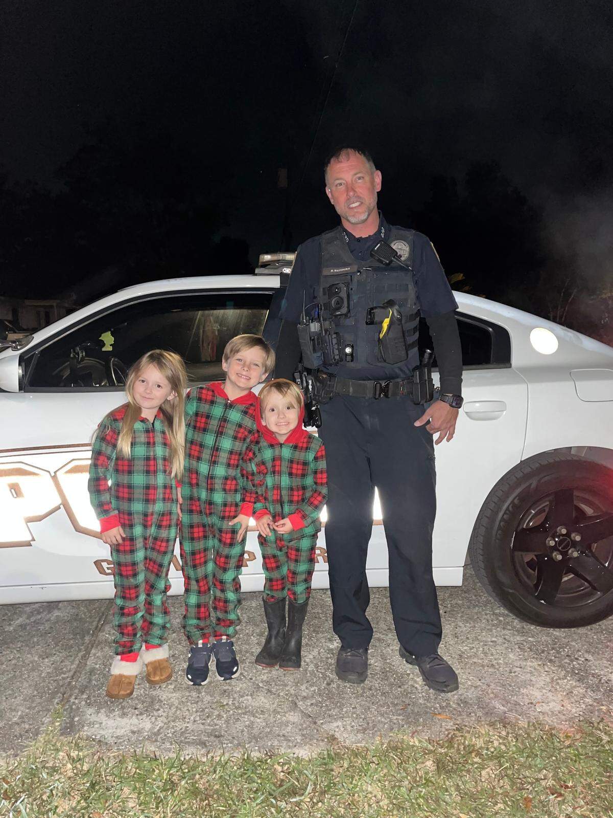 From left, siblings Nellie, Sawyer and Shep Titus stand with Gulfport Police Officer Matthew Mashburn after he took into custody their Elves on the Shelf and brought them by the Titus home to be identified. Mashburn released the elves after the children confirmed the pint-sized Santa’s helpers should not be taken to jail.