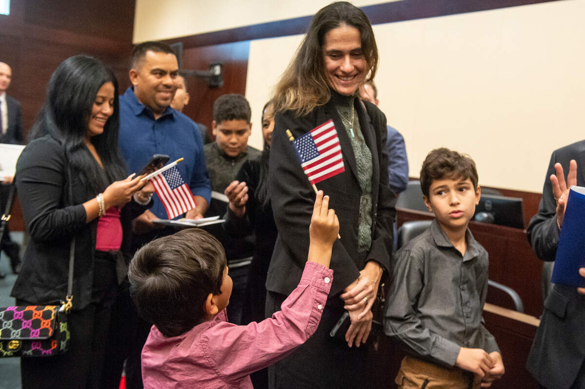 Newly naturalized American citizens wave flags and take photos with their families following a naturalization ceremony at Dan M. Russell Courthouse in Gulfport on Thursday, Oct. 19, 2023.