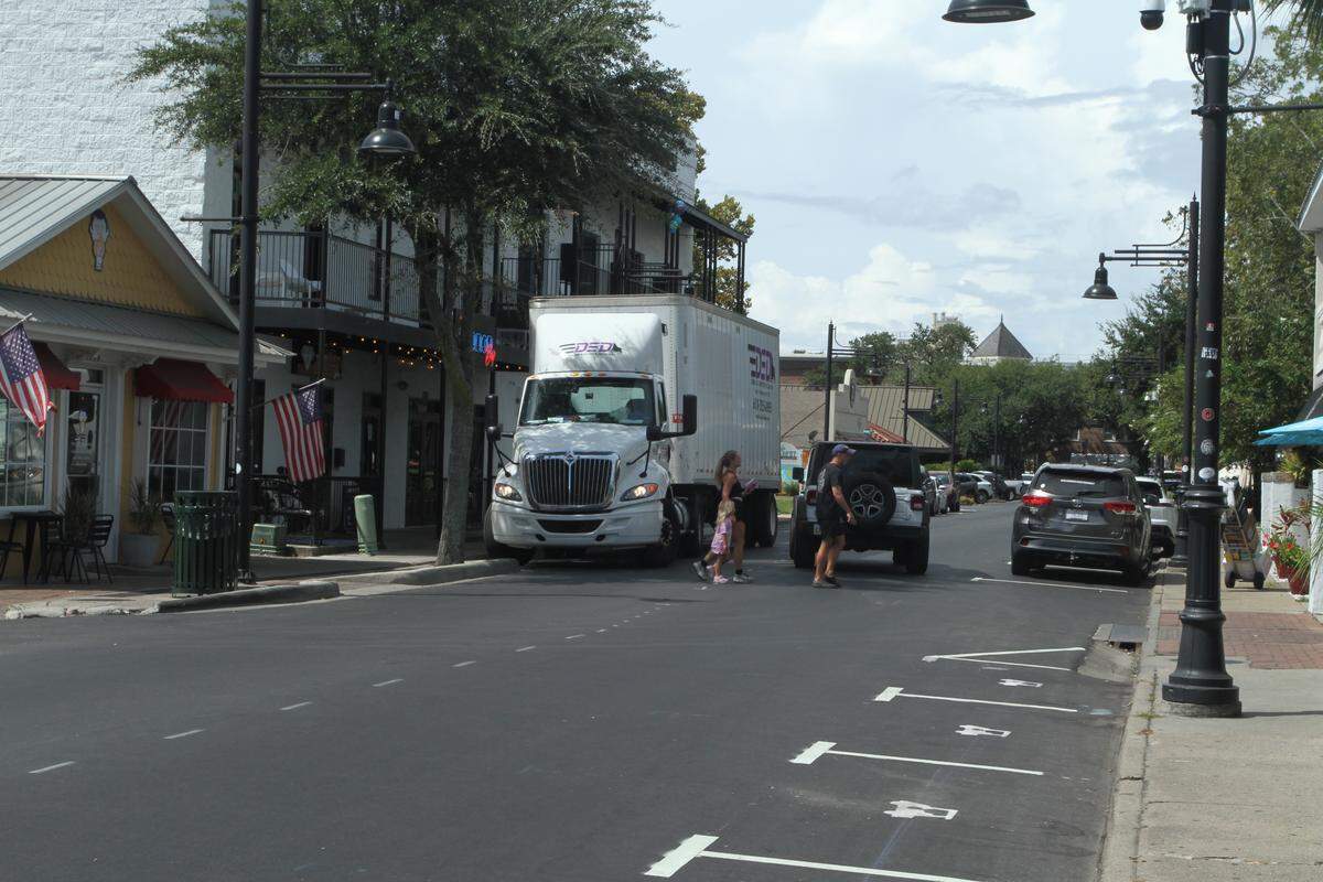 Pedestrians cross Government Street in front of a delivery truck dropping off supplies at a downtown business. Only one lane is available during deliveries on the busy street, where numerous restaurants and bars, offices and retail shops are located.